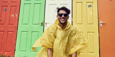 man in raincoat in front of colored doors