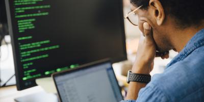 IT professional with desktop and laptop screen in front