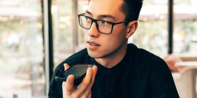 Color photo of bespectacled Asian man talking into a mobile phone