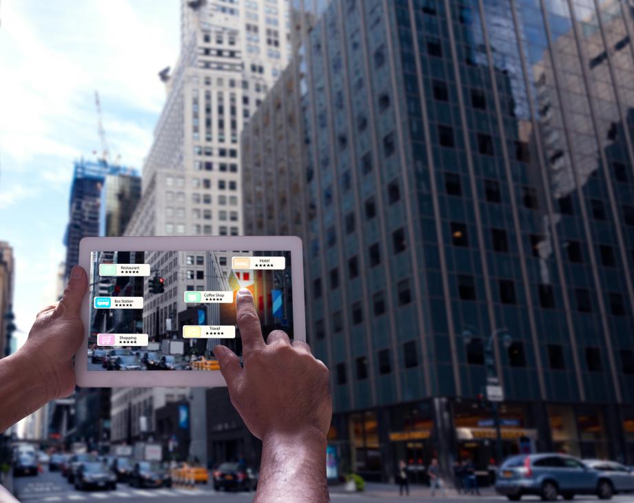person holding tablet in front of skyscraper