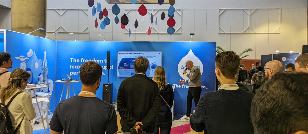 Color photo of Jason Greenspan of Cyber-Duck giving a Lightning Talk at the Acquia booth at DrupalCon Lille